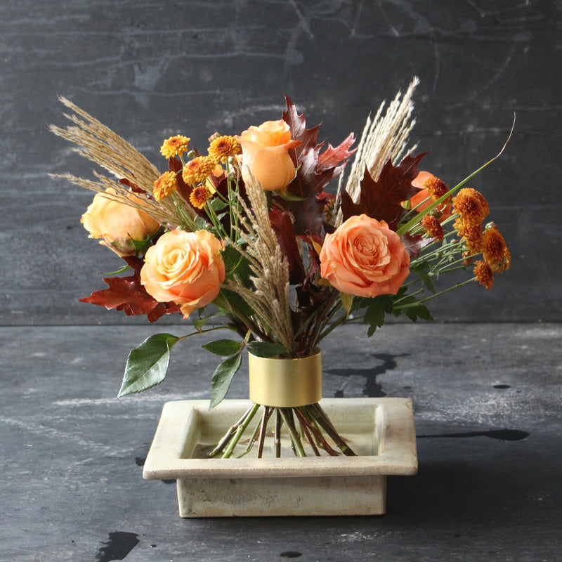 Arrangement Ikebana d'automne avec des roses orange et du feuillage de saison utilisant un support de tiges en spirale Hanataba Champagne Gold.