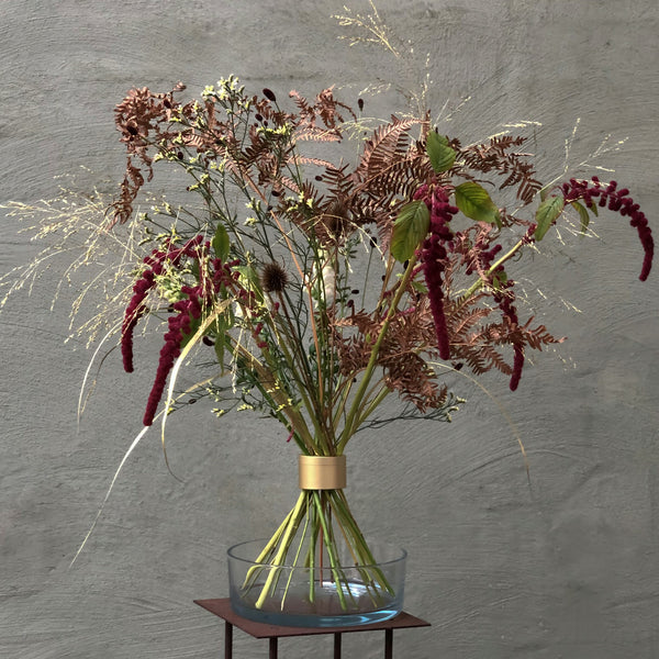 Présentoir d'Ikebana automnal avec des amaranthes rouges et des fougères, artistiquement fixé par un support de tiges en spirale Hanataba.