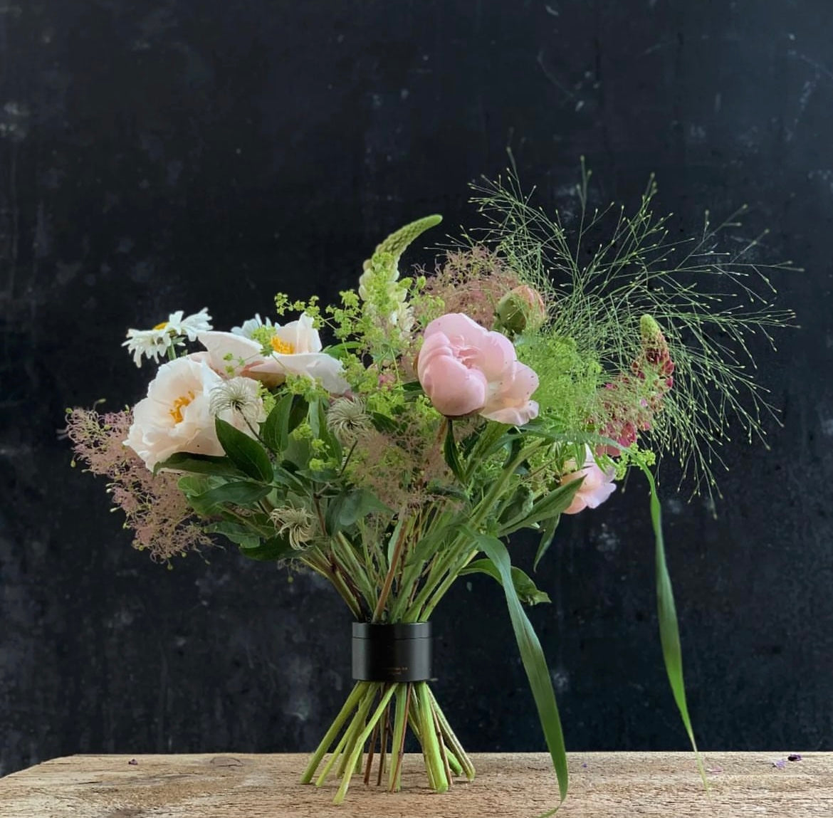 Un bouquet délicat de roses roses, de fleurs blanches et de verdure vaporeuse, soigneusement fixé à l'aide d'un support de tige en spirale Hanataba Bouquet Twister.