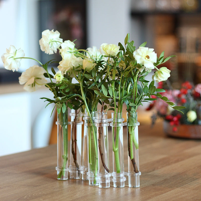 Élégant vase Flowerflute de Hanataba présentant une composition de roses blanches fraîches sur une table en bois.