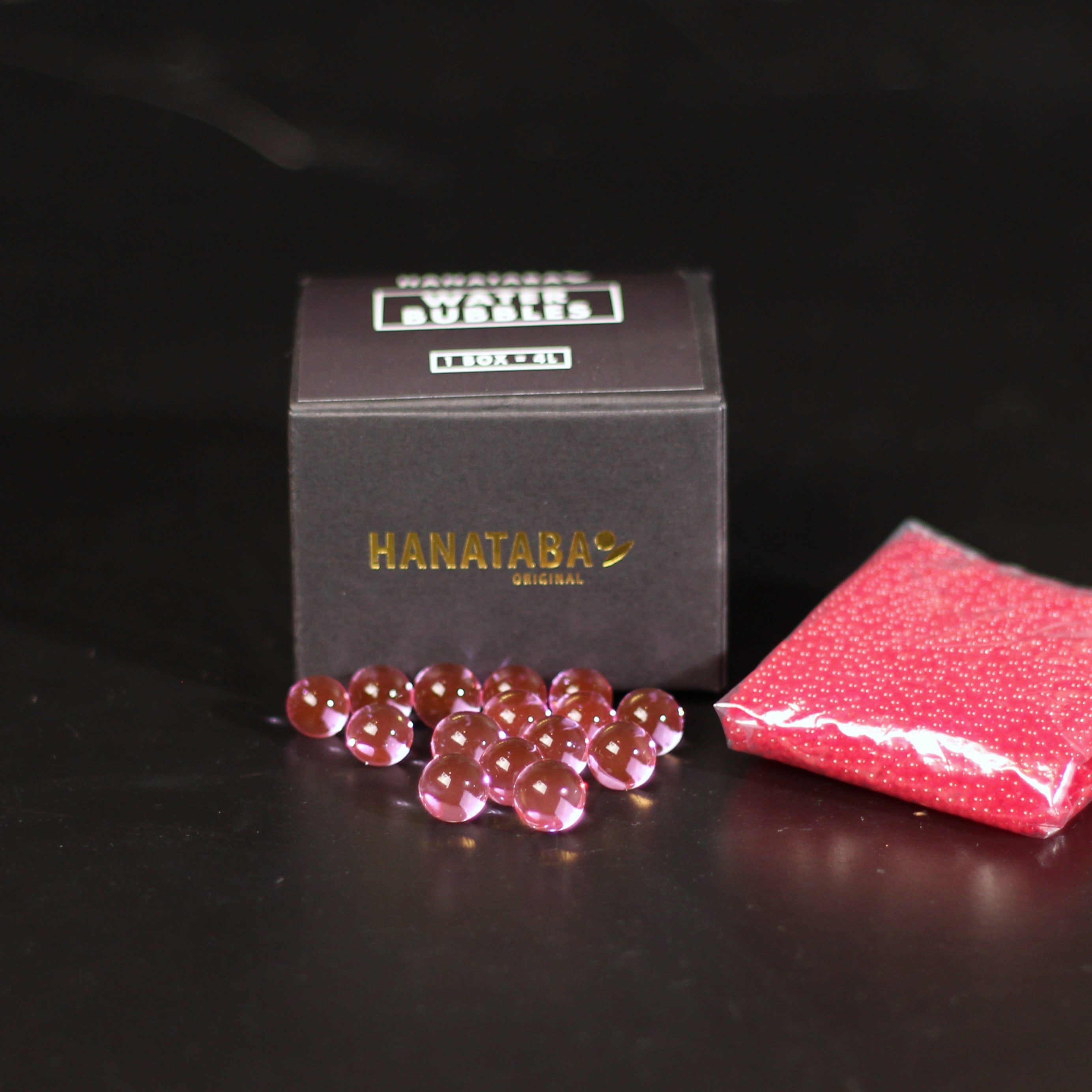 Translucent pink water bubbles next to a 'HANATABA ORIGINAL' box and a packet with a red sparkling texture.