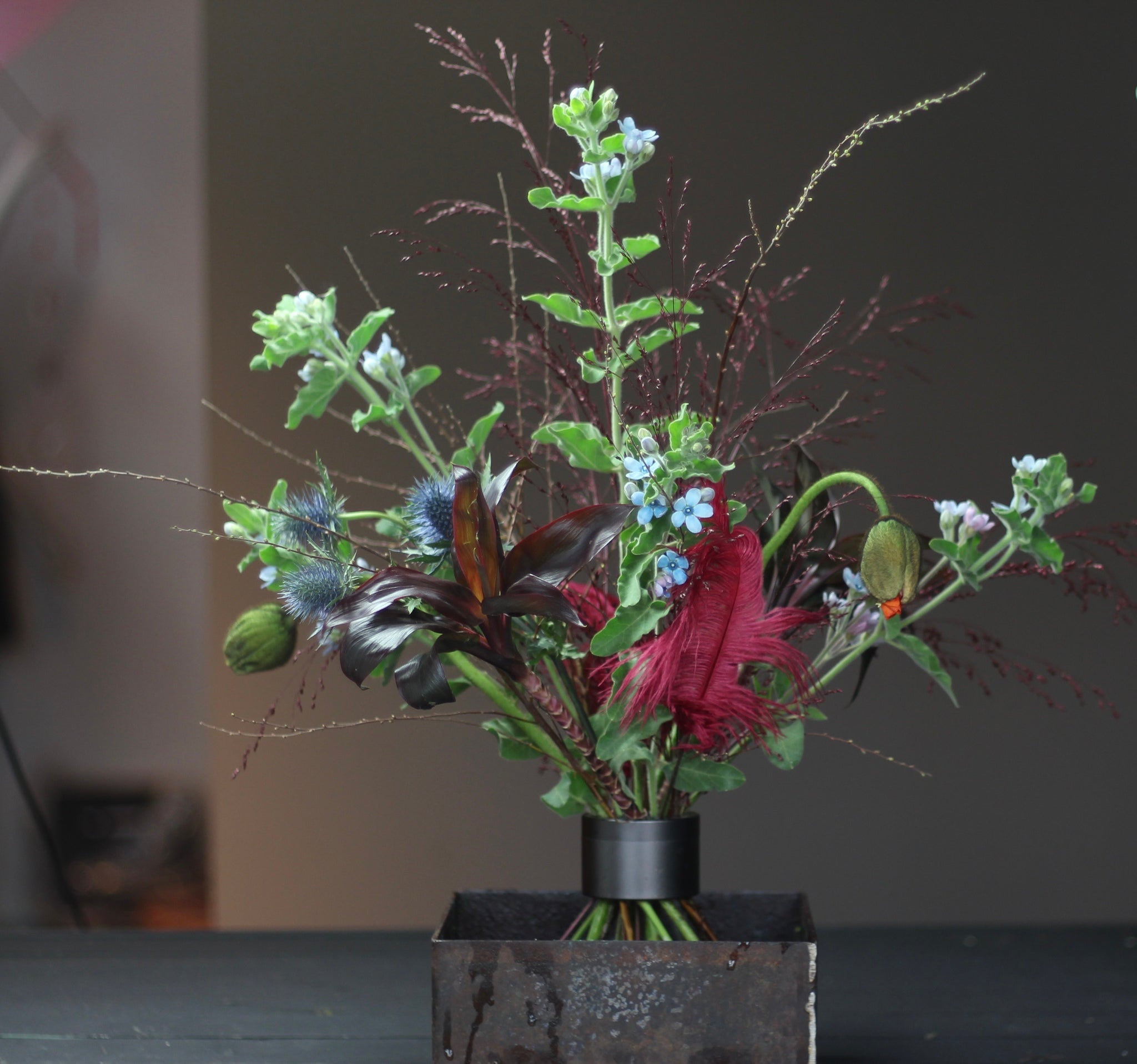 Arrangement Ikebana composé d'une variété de fleurs et de feuillages, fixé à l'aide d'un support de tige en spirale noire Hanataba.