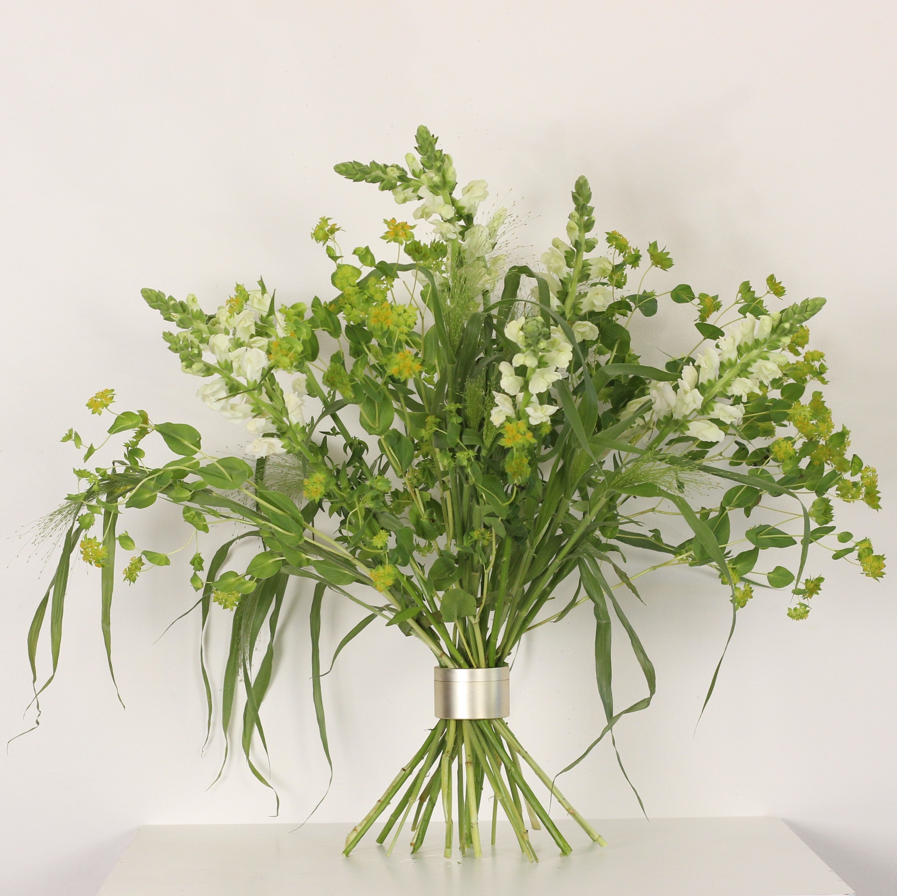 Une composition florale d'inspiration Ikebana en pleine floraison, sécurisée par un Bouquet Twister, mettant en valeur une harmonie de fleurs blanches et jaunes.