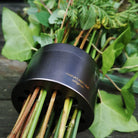 Des tiges de verdure variées sont regroupées dans un support de tiges en spirale noir absolu Hanataba Original, conçu pour créer des arrangements floraux ikebana.