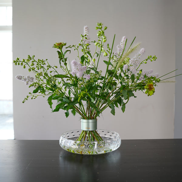 Magnifique bouquet en spirale de couleur pastel présenté dans un vase en verre transparent avec un support de tige design.