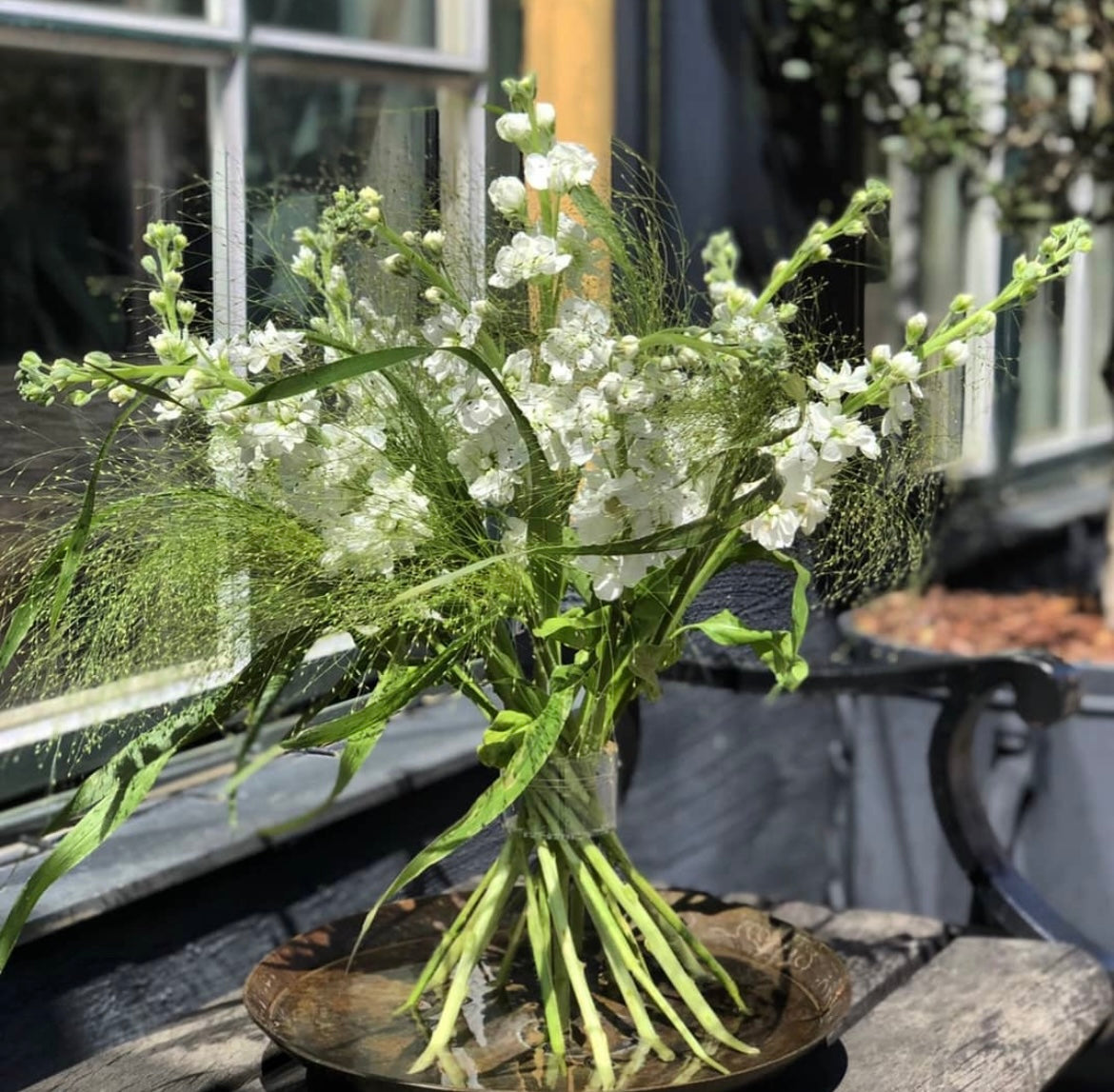 Une composition Ikebana comprenant un assortiment de fleurs blanches délicates, complétée par un support de tiges en spirale Hanataba Crystal Clear pour une touche de modernité.