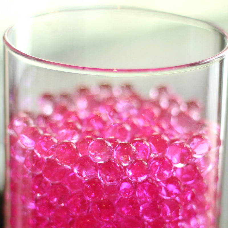 Des bulles d'eau d'un rose éclatant remplissent un vase en verre transparent, ajoutant une touche de couleur à la créativité des compositions florales.