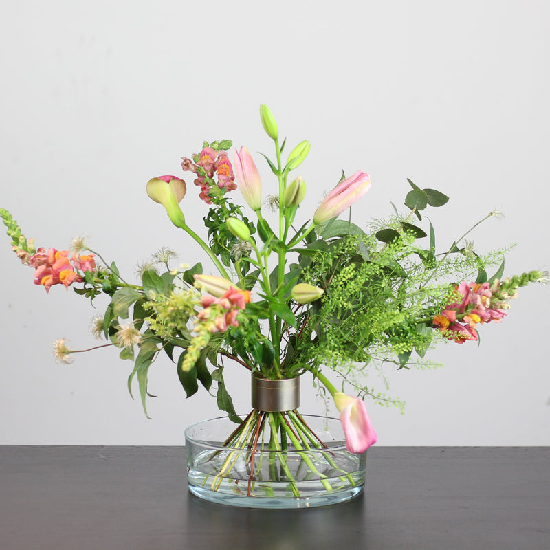 Un mélange varié de fleurs colorées disposées dans un vase clair, maintenues par une torsade de bouquet Hanataba Pitch Black.